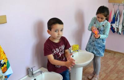 Small children wash their hands in a school setting