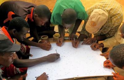 A group of men gather around a map marking various areas.