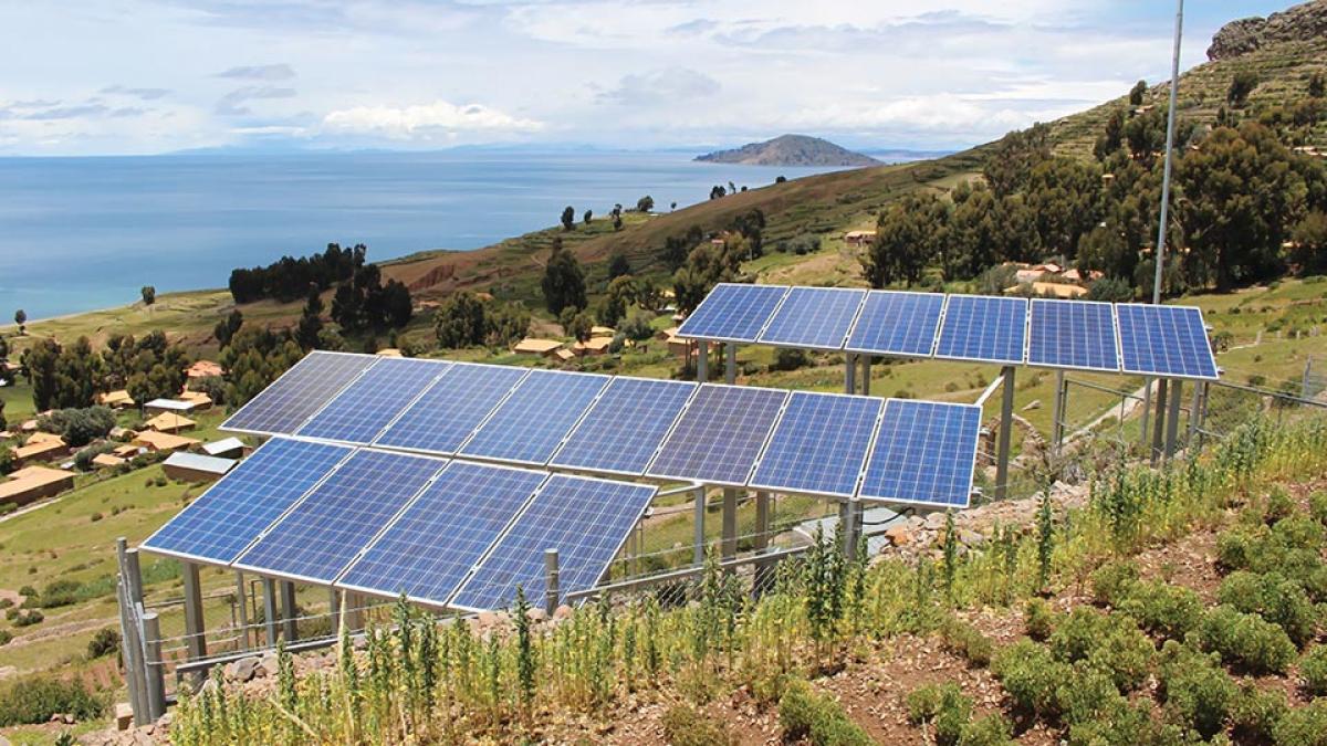 Photo of solar panels on a sunny green hillside shore