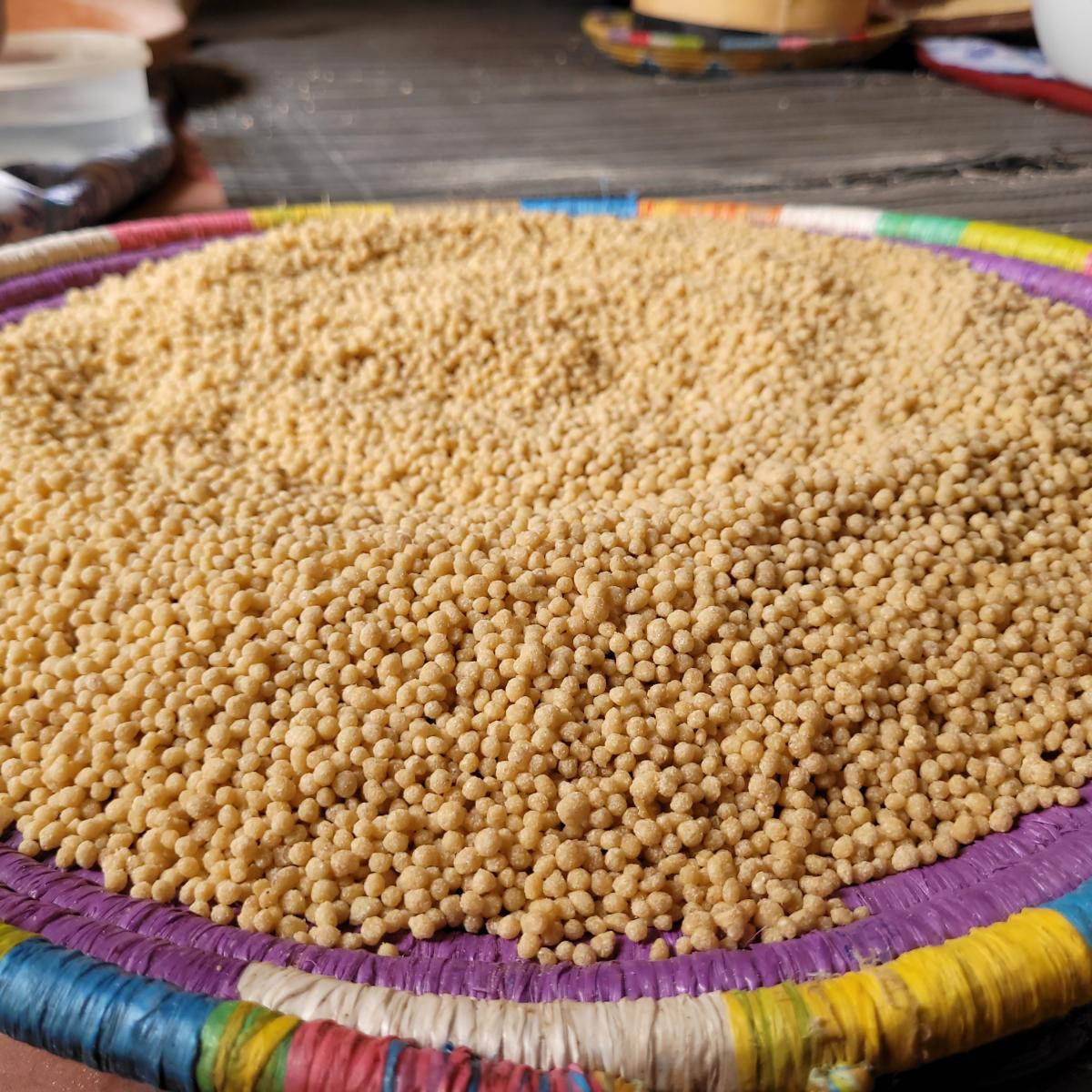 Couscous being processed rests in a colorful wicker bowl