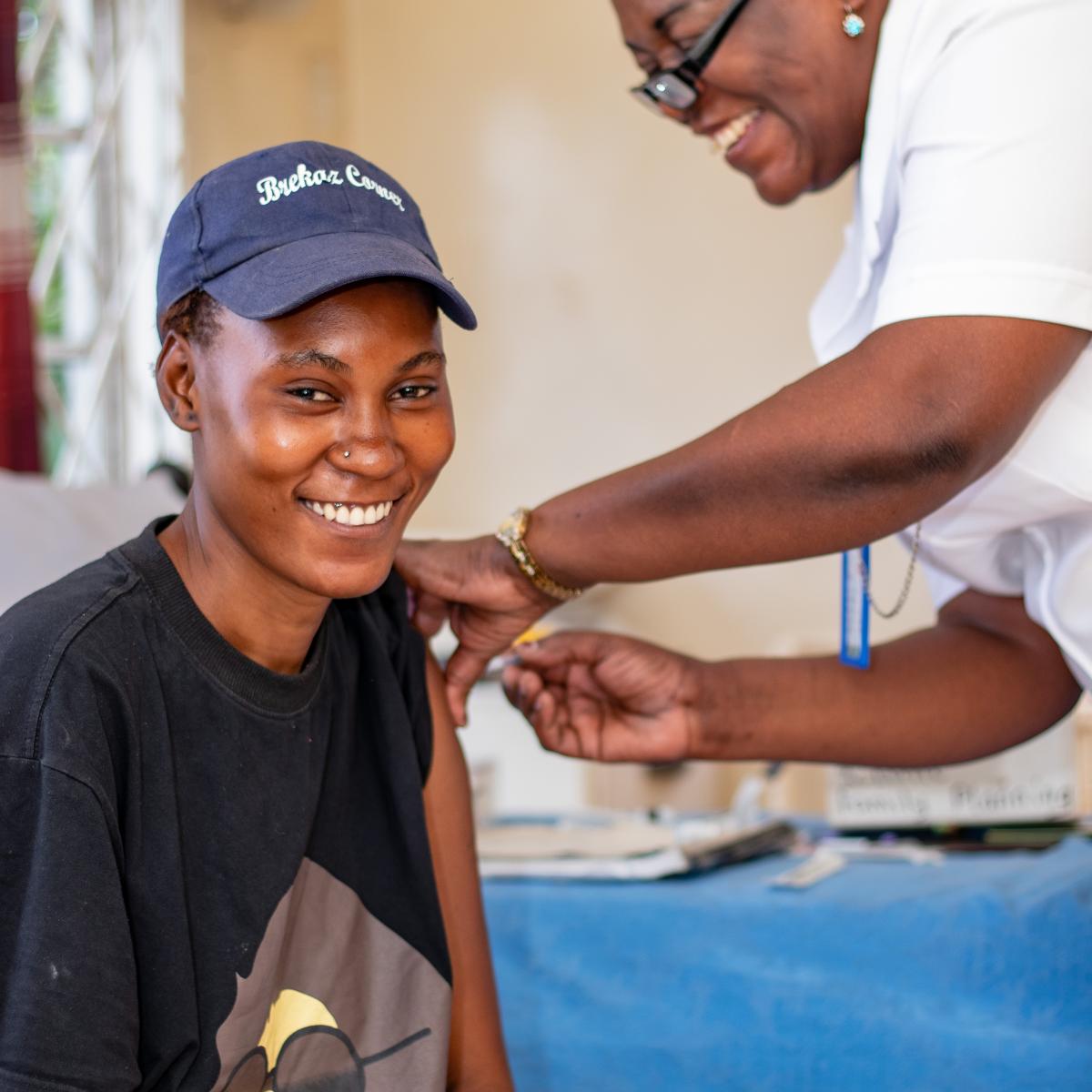 A nurse administers contraceptive to a smiling young Zambian woman in a clinic