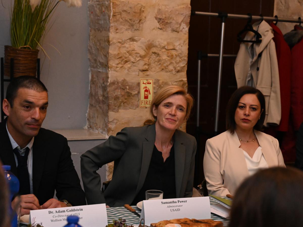 Women seated between a man and a woman intently listening during a seated table discussion.