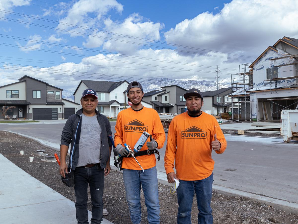 H-2 visa construction workers pose in front of the snowy mountain landscape during their break.
