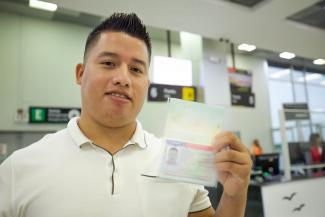 Balmore holds his visa prior to boarding the plane that will take him to work temporary and legally in the United States.