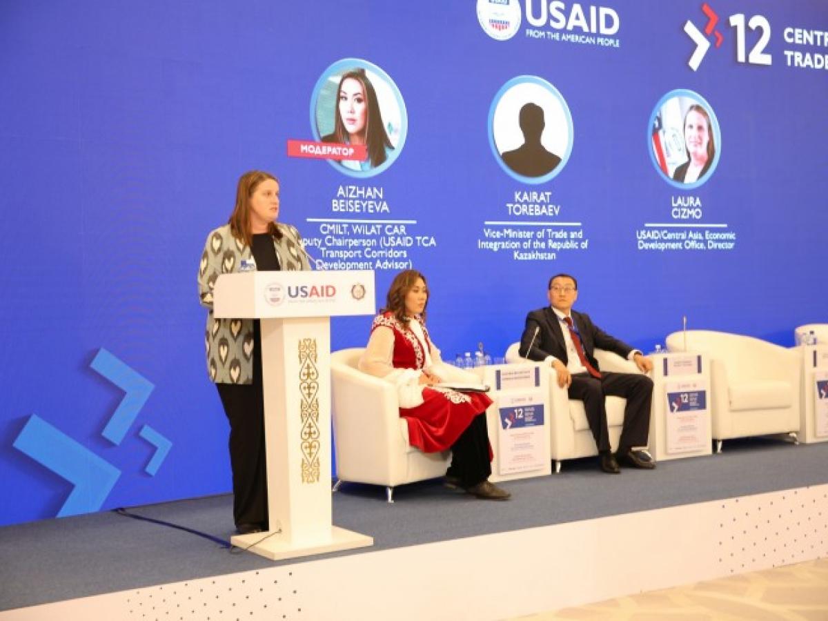 Laura Cizmo presenting opening remarks at the Central Asia Trade Forum with Aizhan Beiseyeva and Karat Torebaev sitting on the right.