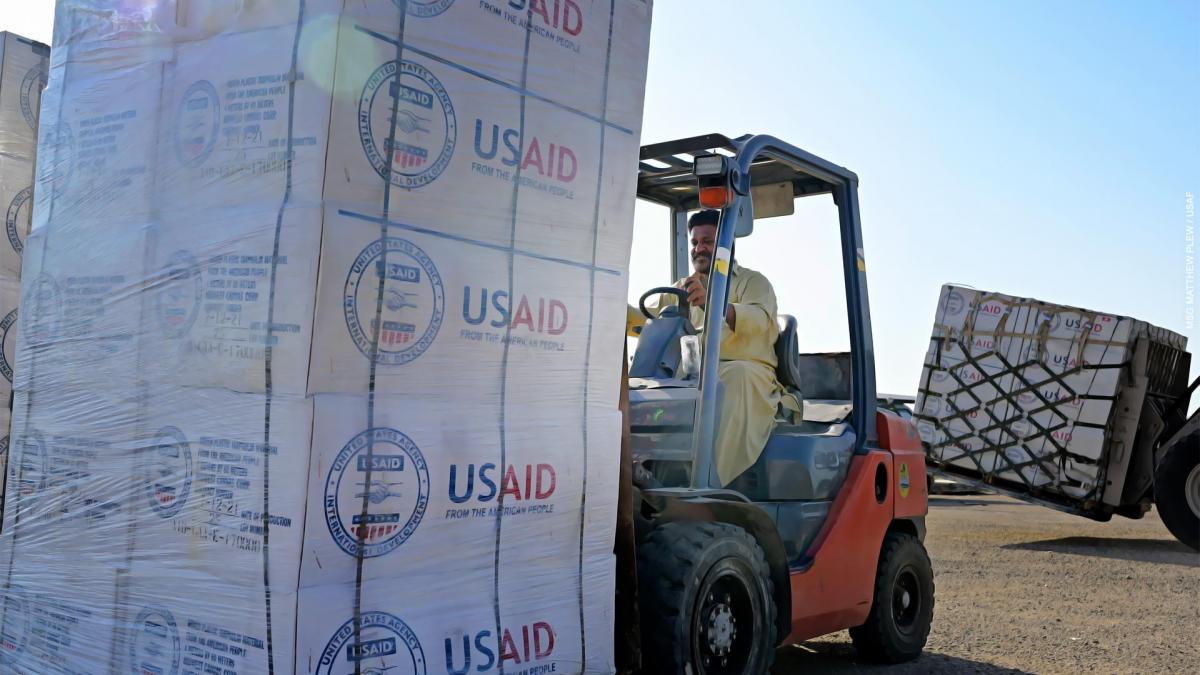 A man moves USAID humanitarian aid supplies with a forklift