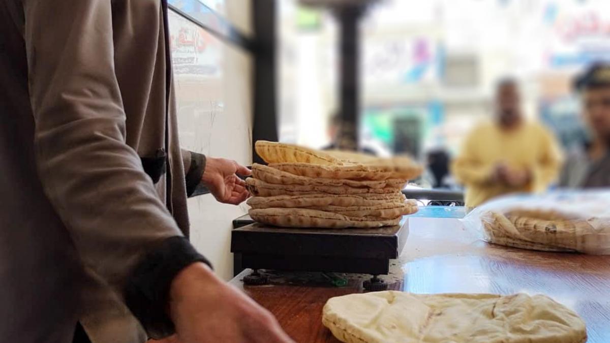 A bakery employee weighs flatbreads to fulfill a customer's order.