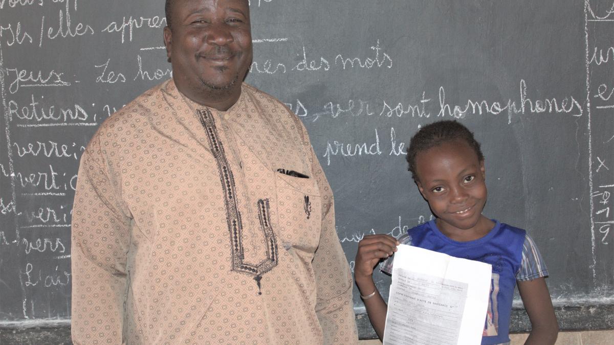 Fatoumata Kené receives her new birth certificate thanks to her godfather, Alphonse Kassogué, who worked with USAID GLEE and local officials to document her birth after the family fled from an extremist attack. 