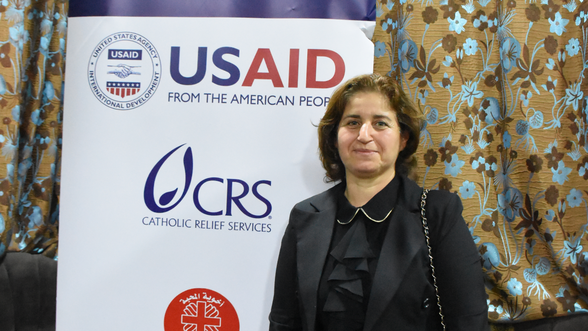 Rajaa Gorgees stands in front of a USAID/Shared Future banner
