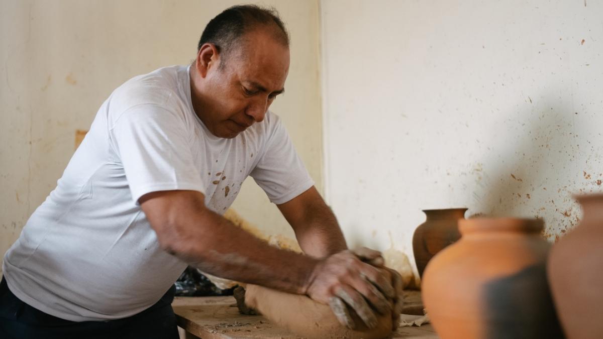 A man kneads clay on a table.