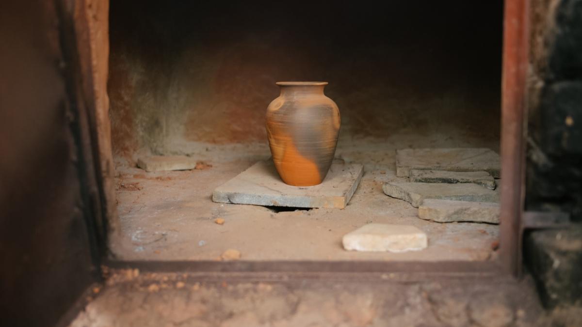 An unfinished clay pot on the floor in a doorframe.