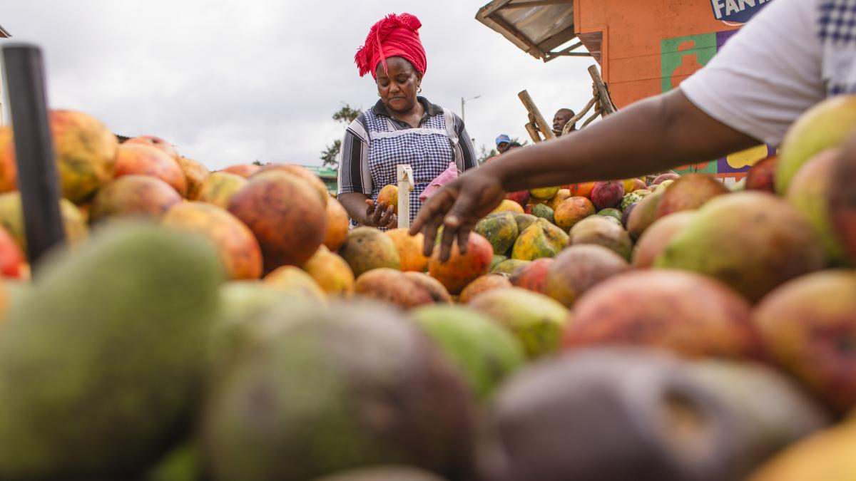 A woman looks at a cart filled with fresh fruits.