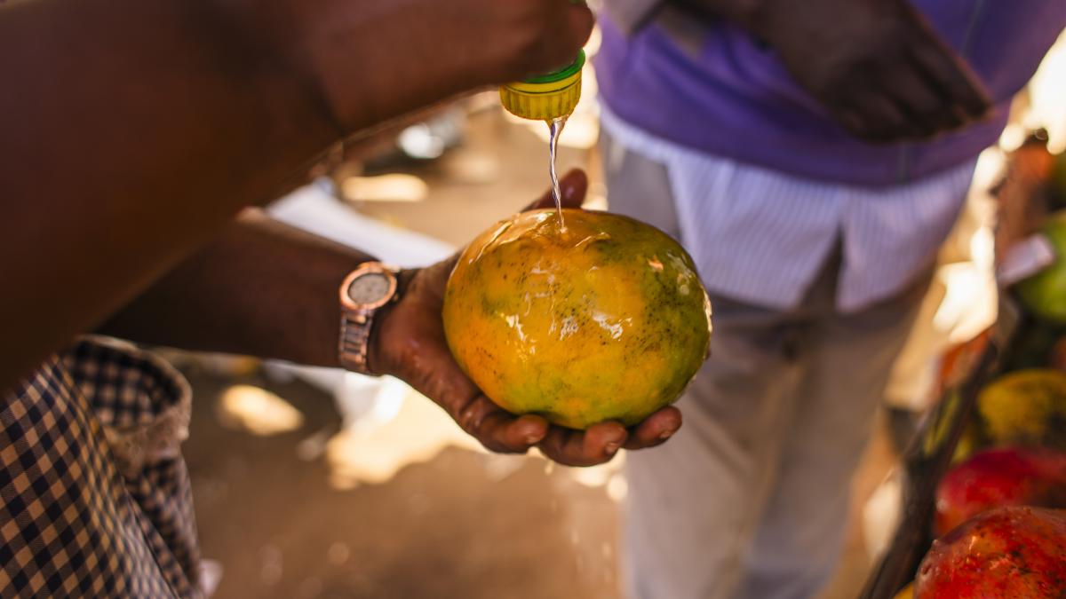 A mango is washed with a small squeeze bottle of water.