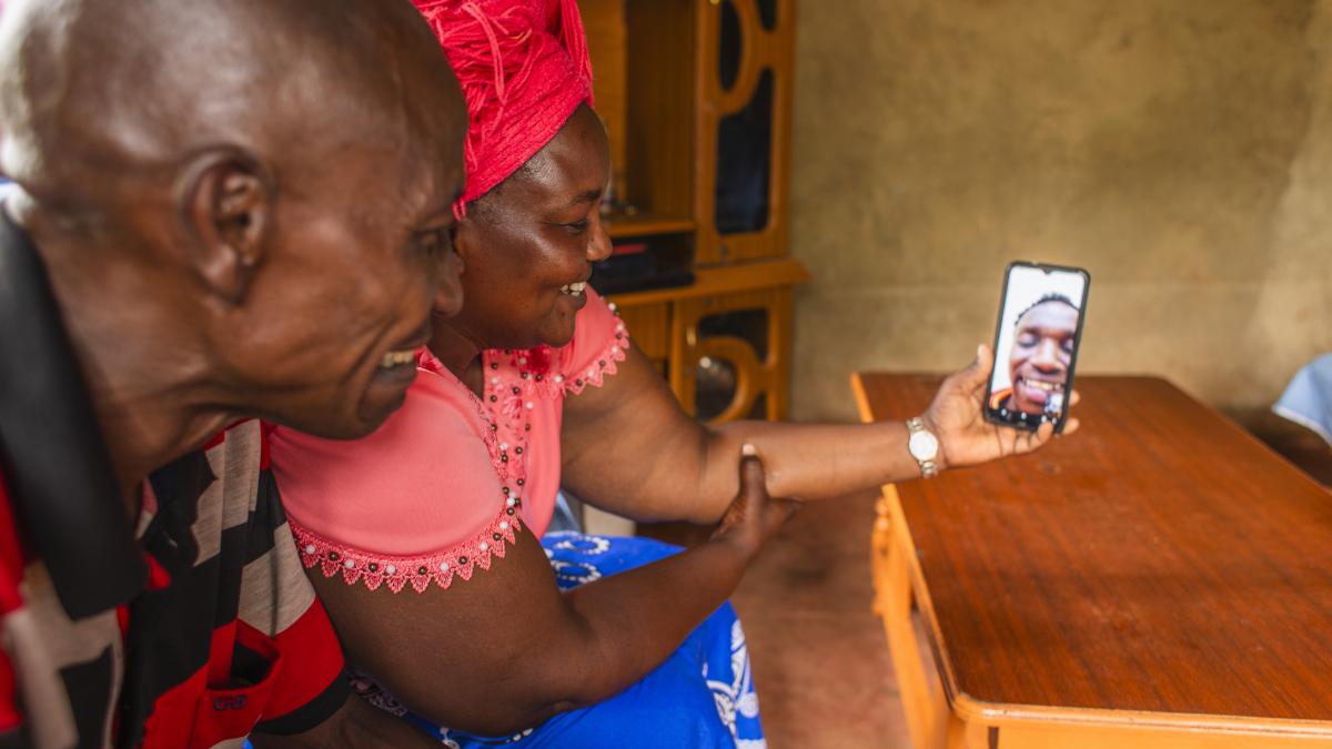 Parents look at their smartphone which shows a picture of their smiling son.