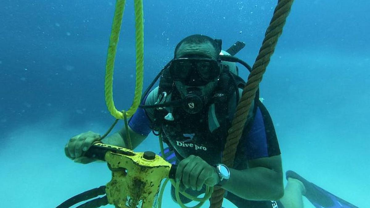 A scuba diver working with drill to install permanent mooring buoy system
