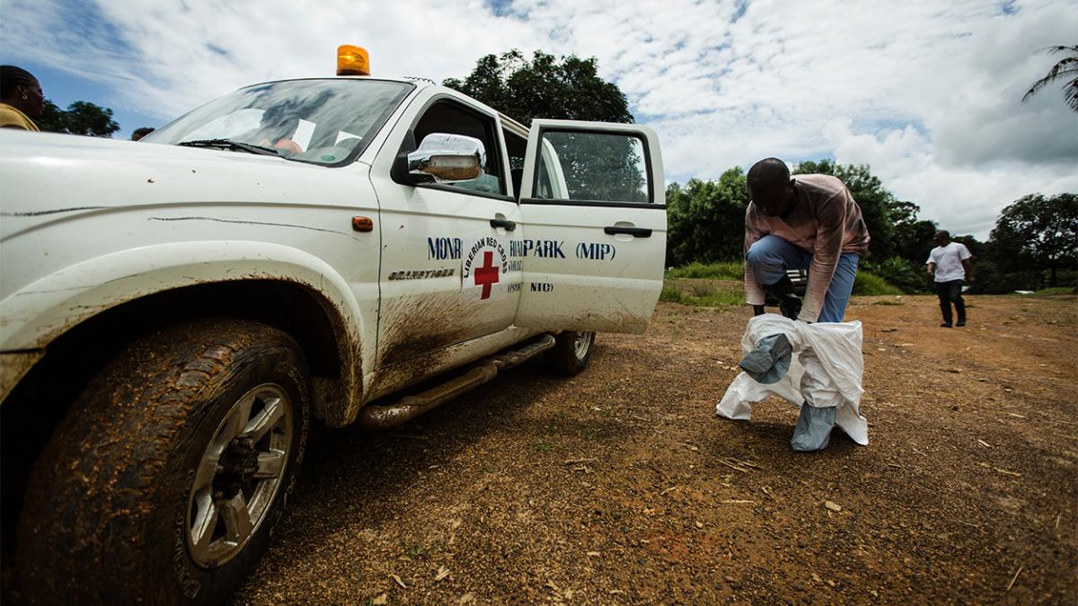 A health worker removes his hazmat suit next to a truck