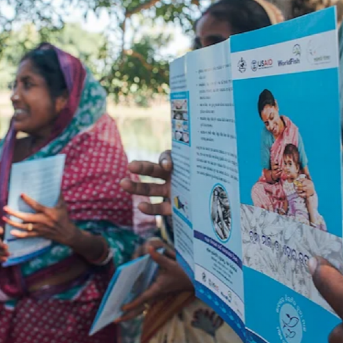 Project staff at a nutrition workshop, organized by the USAID and WorldFish, explain the nutritional value of small fish and enrolled families with backyard ponds to pilot the project. 
