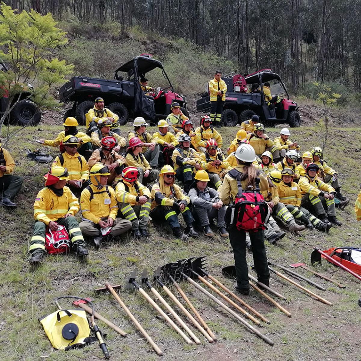 A large of group of firefighters receiving training outdoors