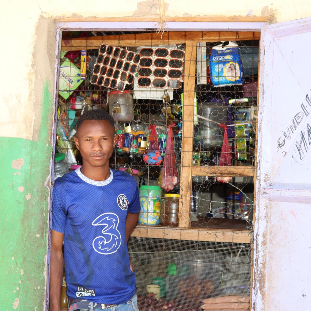 James Lordo stands outside his retail shop as he waits for customers. Photo credit: Saruni Letiwa/USAID