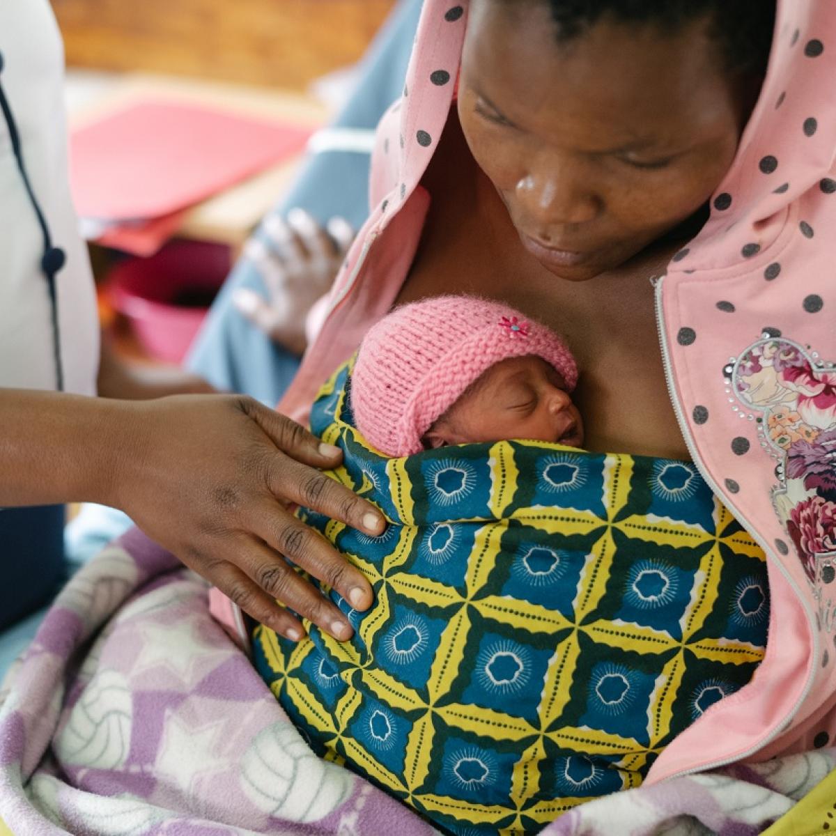 A woman with an infant bundled on her chest.