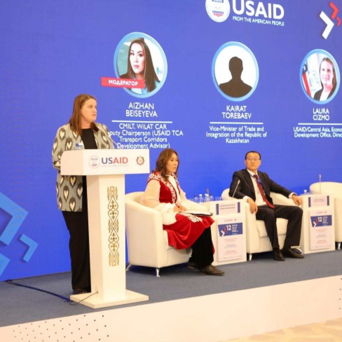 Laura Cizmo presenting opening remarks at the Central Asia Trade Forum with Aizhan Beiseyeva and Karat Torebaev sitting on the right.
