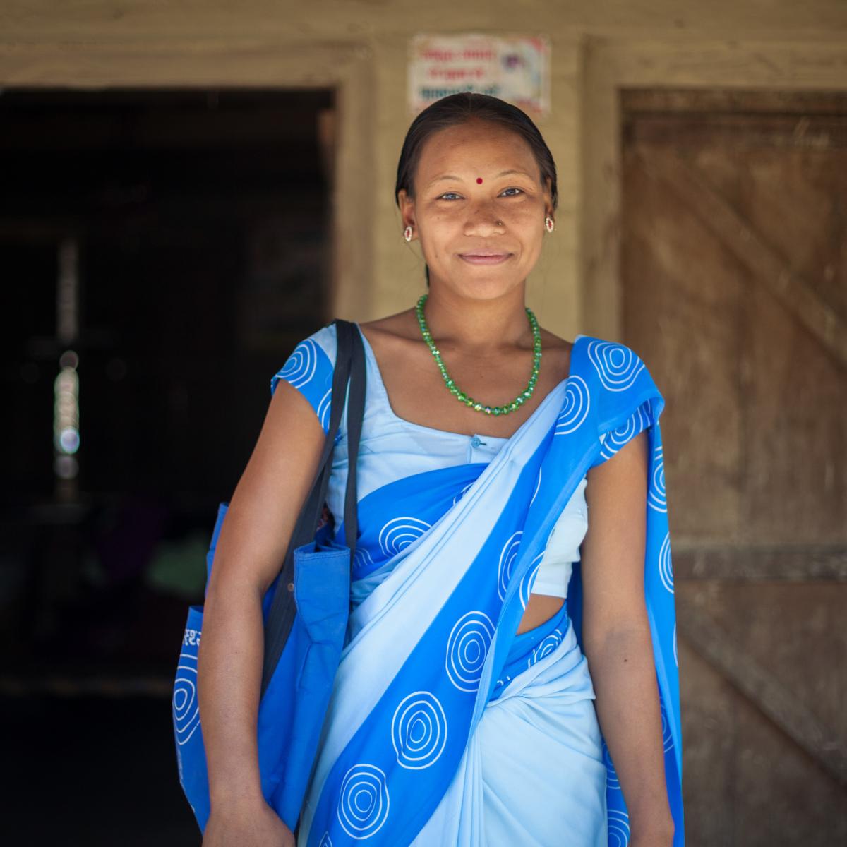 Smiling woman in a blue sari.