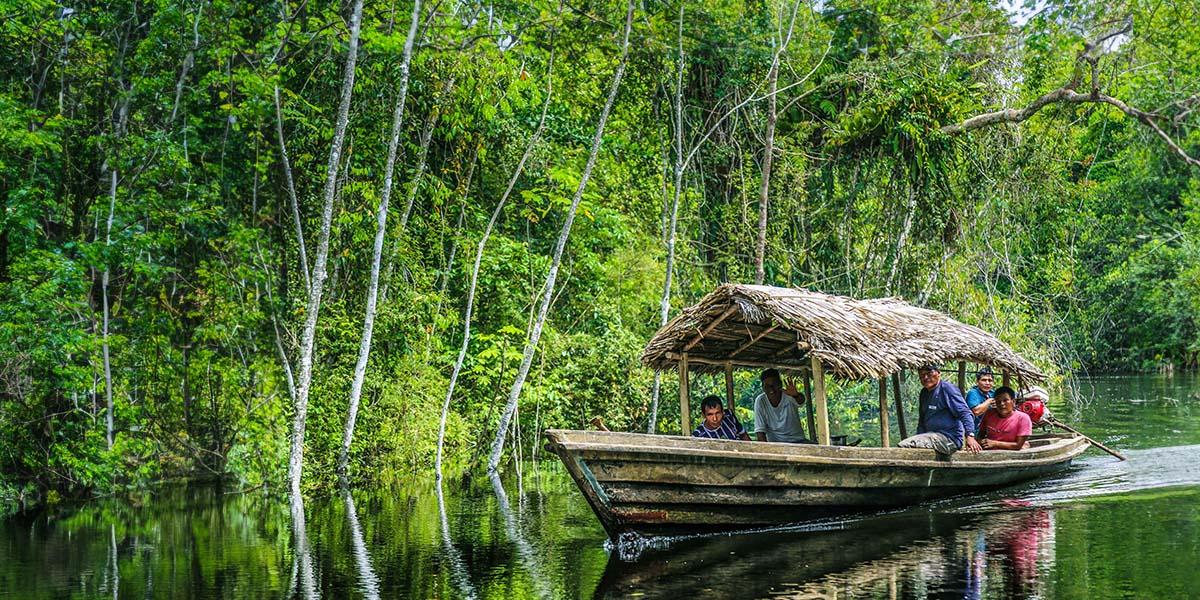 A grup of people on boat sailing on a river in the Amazon rainforest