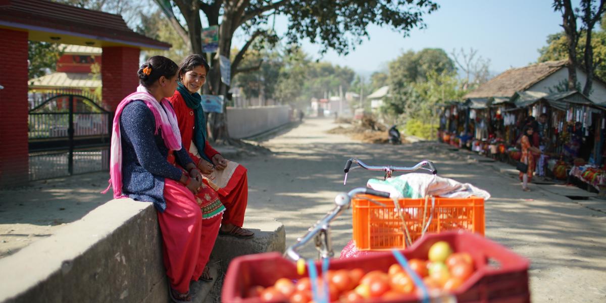 Two women sitting roadside selling vegetables.