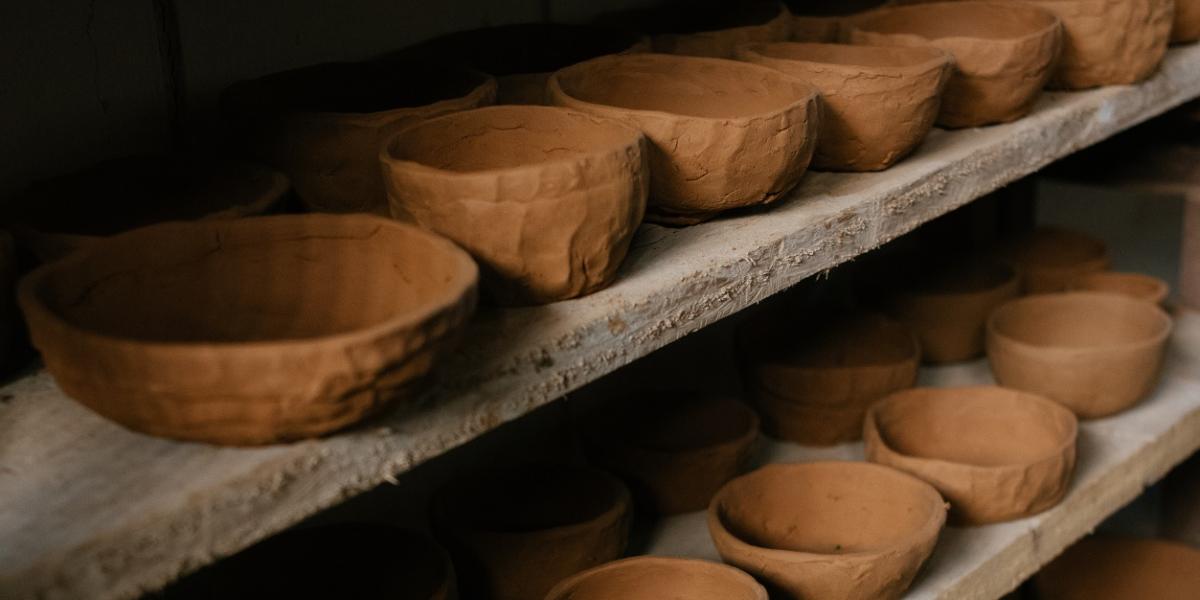 Hand made clay pots lined up on a shelf.