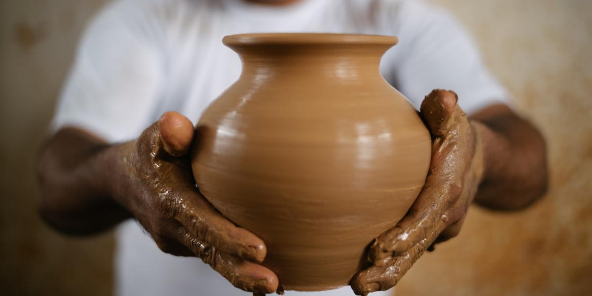 Hands holding a freshly-thrown clay pot.