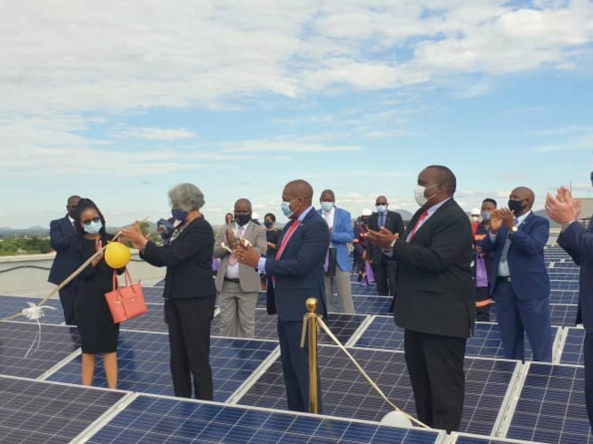 Participants standing between solar panels at the launch of the Rooftop Solar program in Botswana