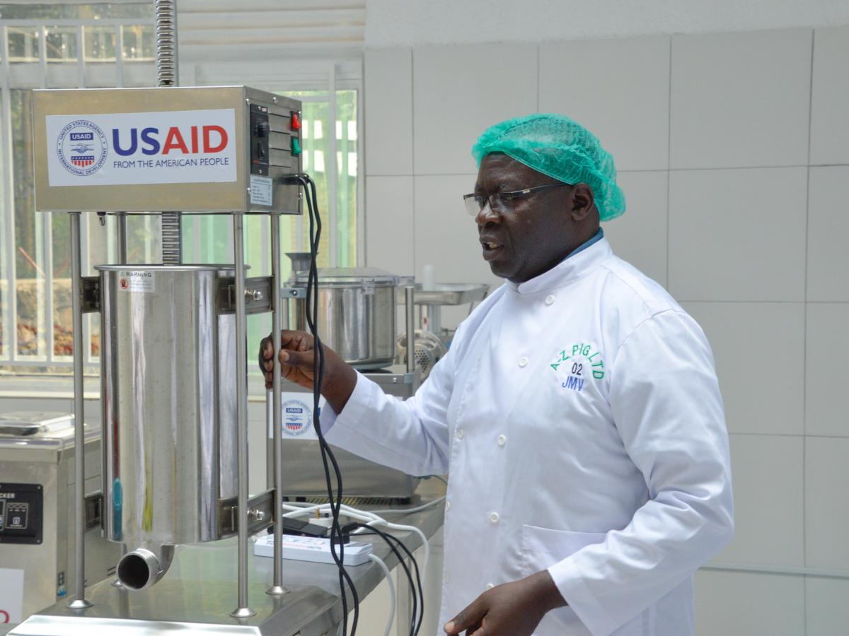 Owner of a butcher shop shows the USAID branded equipment he's using in his business.