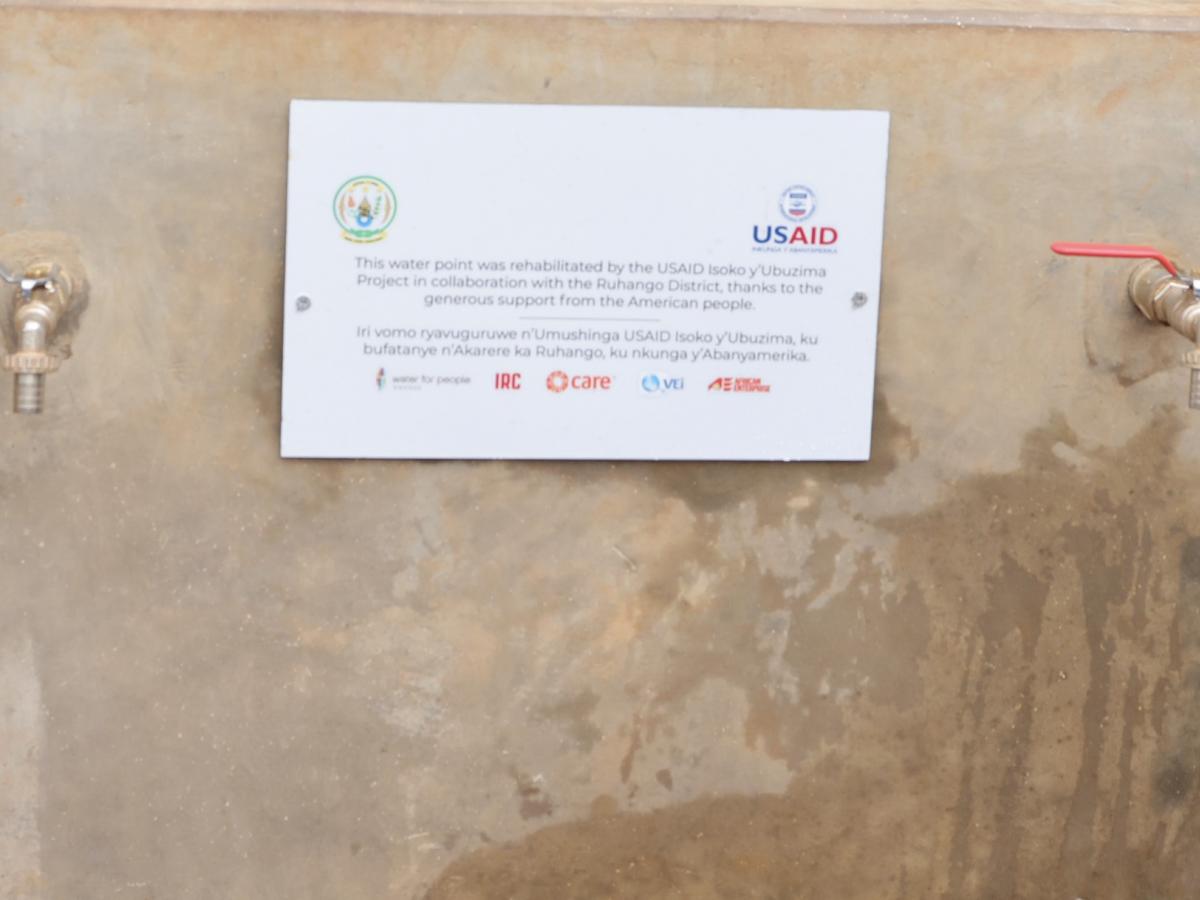 Rehabilitated water source in Ruhango, Rwanda with a plaque commemorating USAID support for this project.