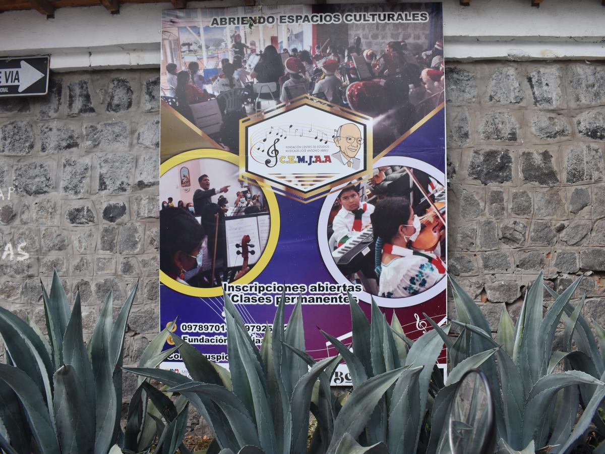 This picture shows a sign with the name and information of the school. It reads: promoting cultural spaces, Center for Musical Studies José Antonio Abreu (CEMJAA), open for registration and courses. 