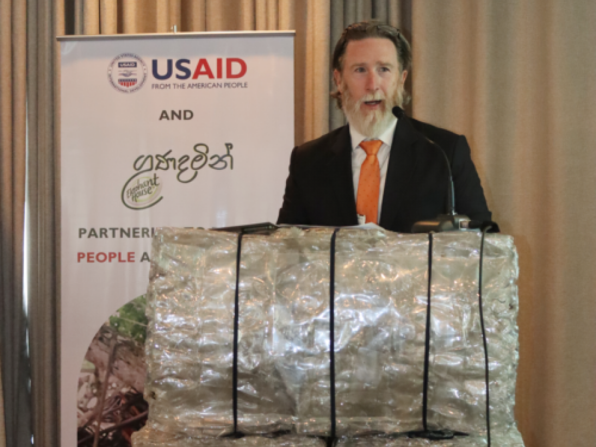 Christopher Powers, Director – Office of Economic Growth, USAID Sri Lanka and Maldives Mission standing behind a podium crafted from baled plastic bottles.