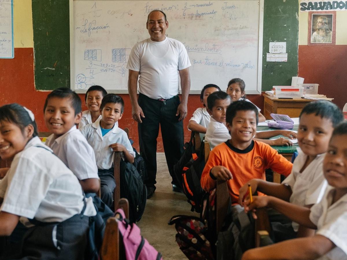 A man stands in front of a classroom of children.