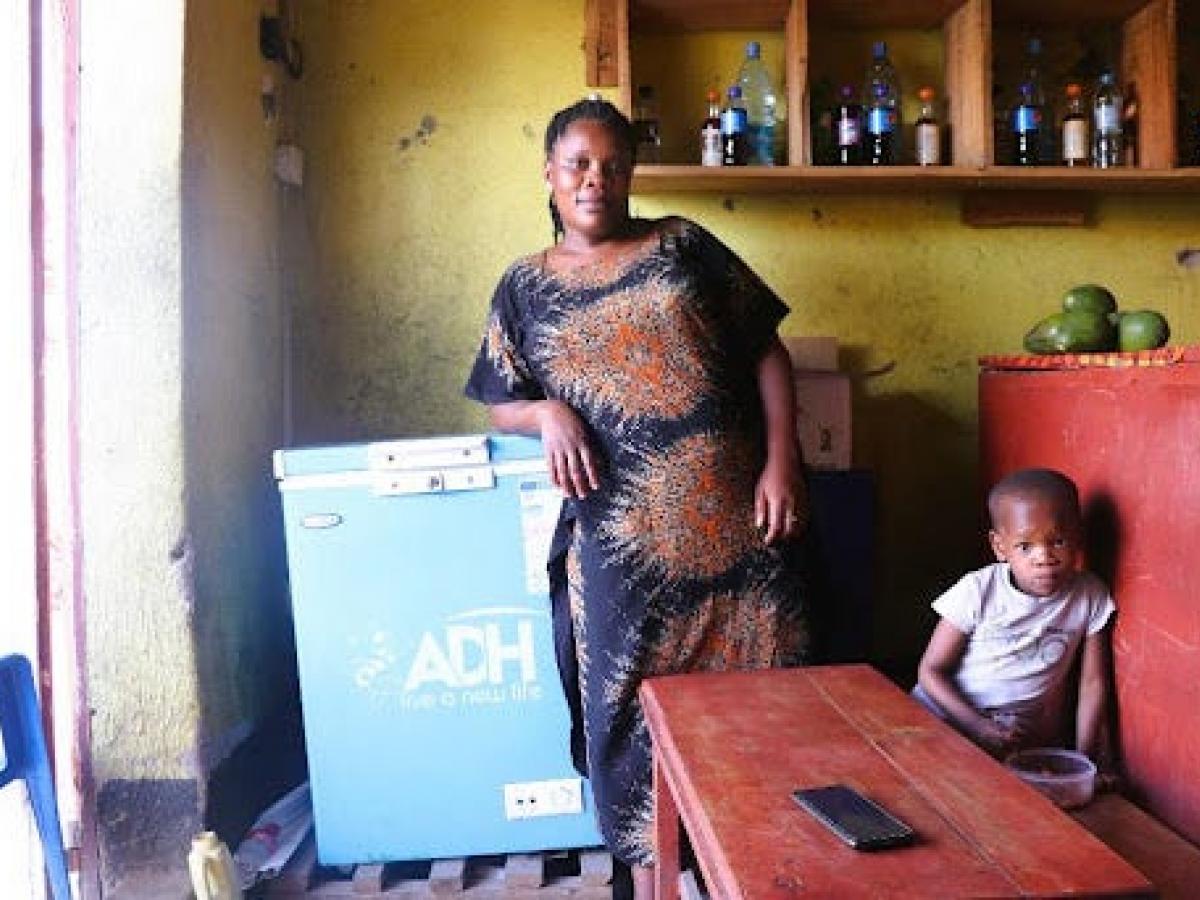 Babra Aikirize, a restaurant and retail shop owner, stands in front of a refrigerator chest in her business. Babra said EEEA’s training has helped strengthen her business acumen. 