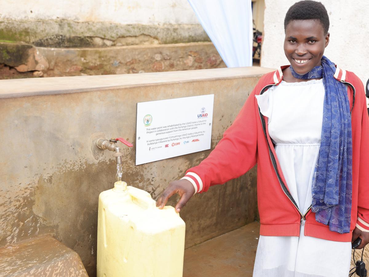 Woman smiling as she fills up her yellow canister full of clean water.