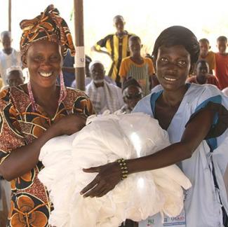 Deux femmes sénégalaises reçoivent des moustiquaires imprégnées d'insecticide grâce à un programme de l'USAID.