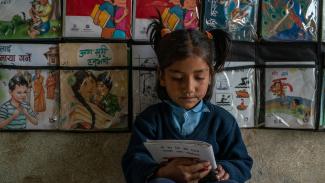Young Nepali girl reads a book at school. USAID is partnering with Nepal to improve educational access and quality.