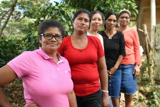Group of indigenous Honduran women pose a group and smile at the camera.