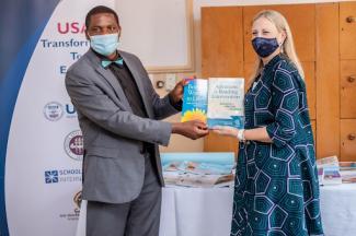 Chalimbana University Deputy Vice Chancellor Dr. William Phiri receives library materials from USAID/Zambia Education Office Director Sarah Crites