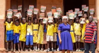 THIRD-YEAR STUDENTS AT A PRIMARY SCHOOL IN TAMALE, NORTHERN REGION OF GHANA, POSE WITH LEARNING MATERIALS DONATED BY USAID