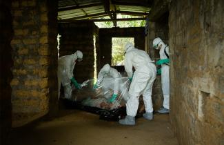 Health workers wrap a deceased Ebola victim