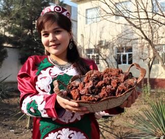 A woman in a traditional outfit poses with a basket of mushrooms 