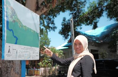 A woman points to a map posted in her neighborhood identifying the disaster-prone areas.