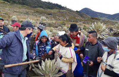 A group of indigenous Guambianos in Colombia circle around scientists explaining the importance of healthy soil. 