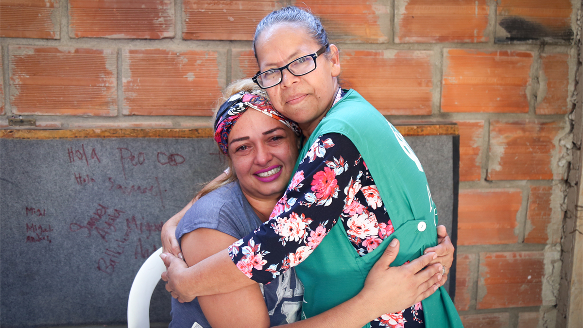 Two women, a beneficiary and aid worker, embrace.
