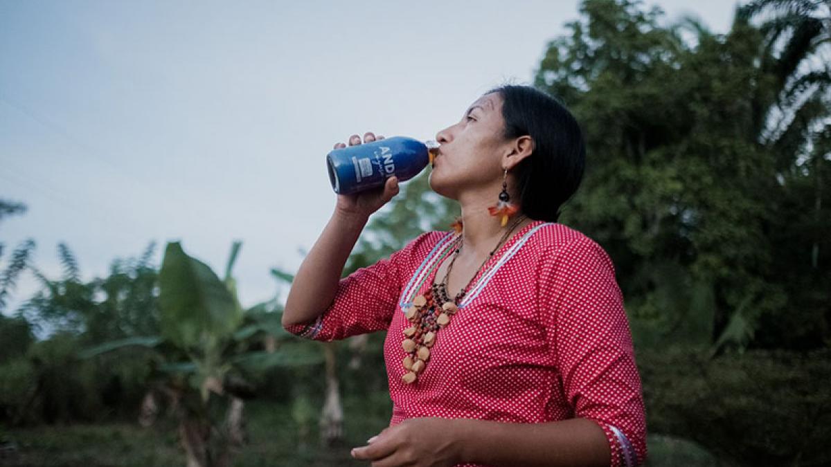 An indigenous woman drinking from a bottle of an Amazonian energizing beverage