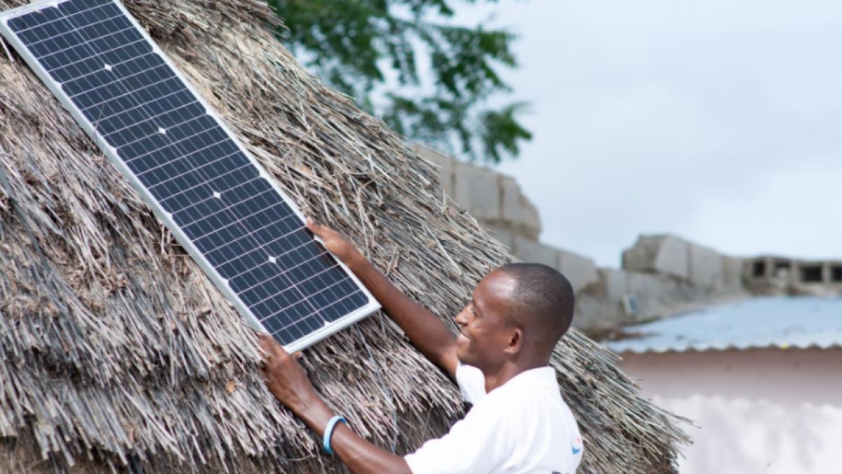 Un agent de Baobab Plus pose un panneau solaire sur une maison